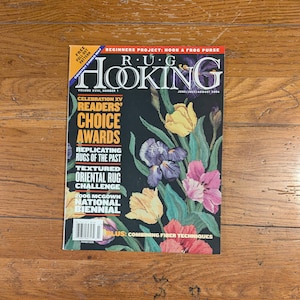 Könnte beinhalten: Ein Zeitschriften-Cover für "RUG HOOKING" mit floralen Illustrationen. Das Cover zeigt Texte wie "Readers' Choice Awards" und "Oriental Rug Challenge". Das Magazin liegt auf einer Holzoberfläche.