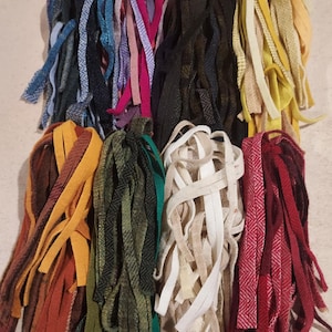 May include: Assortment of colourful wool yarn strips in various textures and patterns. The yarn is arranged in bundles and ready for crafting projects.