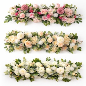 Puede incluir: Tres arreglos florales con flores rosas, melocotón y blancas, y hojas verdes. Los arreglos se presentan sobre un fondo blanco, resaltando los colores y texturas de las flores. Las flores incluyen rosas e hortensias.