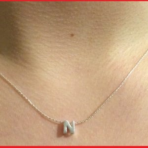 May include: A silver chain necklace with a silver letter N pendant.