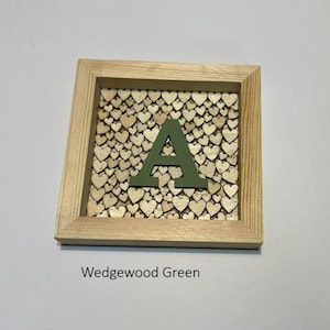 May include: A square wooden frame containing a background of numerous small, light-colored wooden hearts. Centered on top of the hearts is a large, solid letter A in a matte Wedgewood green color. The text Wedgewood Green appears below.