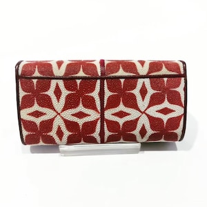 Op de afbeelding: Een rechthoekige portemonnee met een rood-wit bloemmotief. De portemonnee heeft een donkerbruine rand en wordt op een transparante standaard gepresenteerd. Het ontwerp heeft een herhalend patroon van rode bloemvormige vormen op een witte achtergrond.