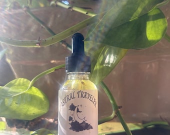 May include: A small glass bottle with a black dropper top and a white label. The label says "Astral Traveler" and "Aids in Astral Travel, Astral Projection & lucid dreaming" and "Vemoja Wicked Herbs".