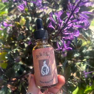 May include: A small brown glass bottle with a dropper top. The label reads "Do As I Say" with a black and white illustration of a person with an eye in their chest. The label also reads "Yermoja Wicked Herbs".