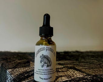 Puede incluir: Una pequeña botella de vidrio ámbar con un gotero negro. La botella está etiquetada con "Cerberus Guard Oil" y presenta una ilustración en blanco y negro de un perro de tres cabezas. La etiqueta también incluye el texto "Guard, Protect, Break any Barriers. Ensure nothing escapes or attempts to enter. Prevent anything from crossing a Barrier. Boundary, Safeguard, Keep drawing a Barrier. Boundary. Simply a Barrier." y "Vermoja Wicked Herbs."