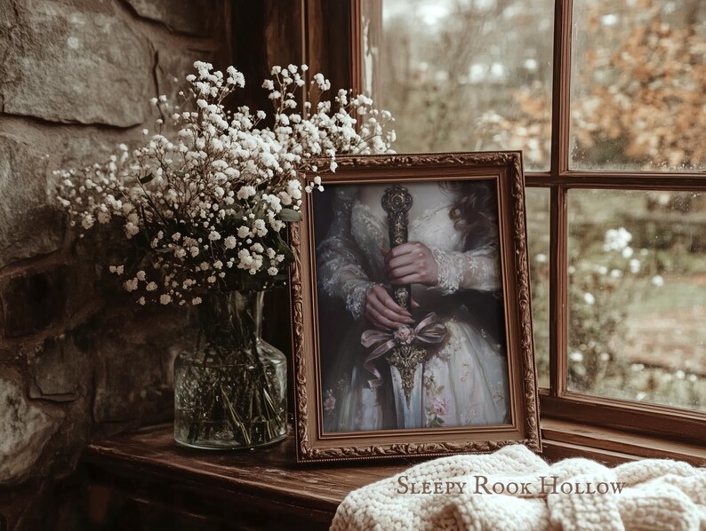 May include: A framed portrait of a person holding a sword with a pink ribbon. The portrait is in a brown frame and is sitting on a wooden surface. The text "SLEEPY ROOK HOLLOW" is visible below the frame.
