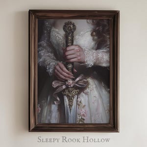 May include: A framed painting of a woman in a white dress holding a decorative sword with a floral design. The sword has a gold and silver finish and is adorned with pink and white flowers. The woman's hands are visible, and she is wearing a white lace dress with floral accents. The frame is brown wood.