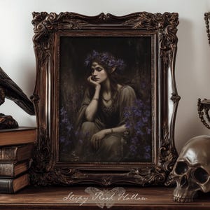 Puede incluir: Una impresión enmarcada oscura y ornamentada de una mujer con una corona floral, rodeada de flores moradas. También hay una estatua de cuervo de bronce, libros antiguos, una calavera y un candelabro. La impresión está firmada "Sleepy Roost Hollow".