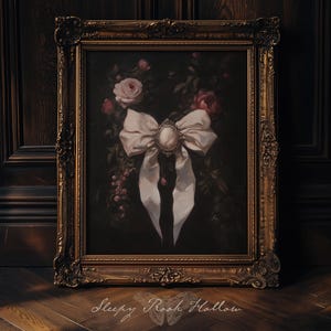 May include: A framed painting featuring a large white bow with a cameo in the center, set against a dark background with roses and foliage. The ornate gold frame adds a vintage touch. The text "Sleepy Rooh Hollow" is at the bottom.