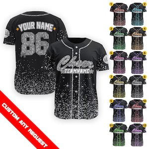 Peut inclure: Un maillot de baseball noir avec des paillettes argentées et le texte "Cheer TEAMNAME" sur le devant. Le maillot a un col blanc et des bordures blanches. L'image montre 12 variations de couleurs différentes du maillot.