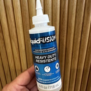 May include: A bottle of Liquid Fusion performance adhesive. The label is blue and white, with the words "Heavy Duty Resistent" and "Dries Clear". The bottle contains 118 mL of adhesive.