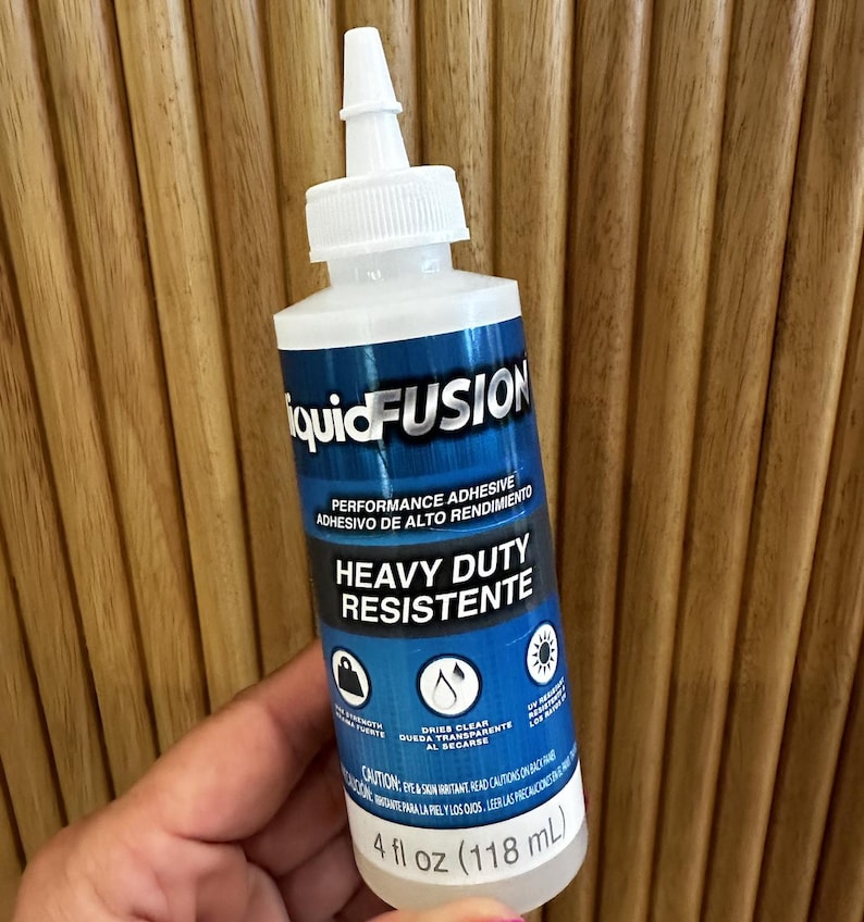 May include: A bottle of Liquid Fusion performance adhesive. The label is blue and white, with the words "Heavy Duty Resistent" and "Dries Clear". The bottle contains 118 mL of adhesive.
