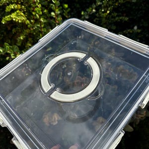 Puede incluir: Contenedor de almacenamiento de pl&aacute;stico transparente con un asa blanca en la tapa. El contenedor est&aacute; vac&iacute;o.