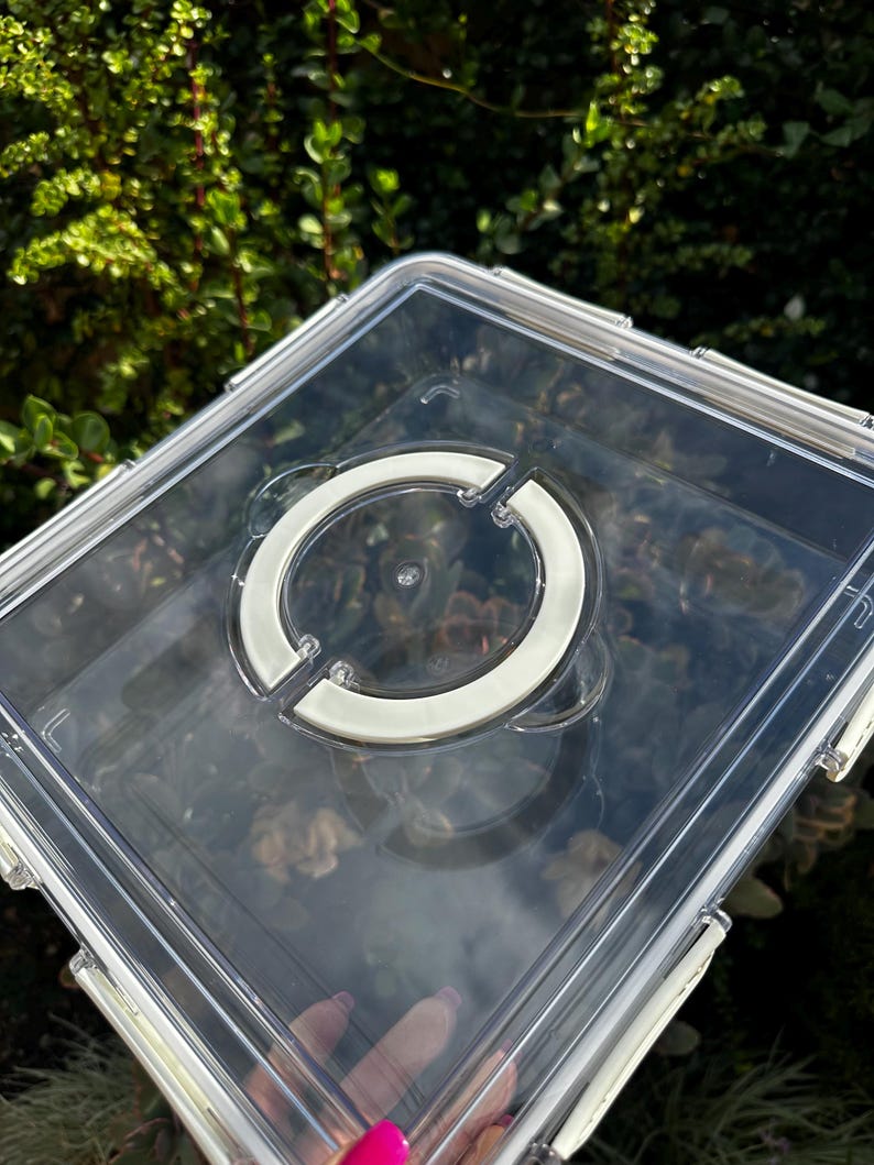 Puede incluir: Contenedor de almacenamiento de pl&aacute;stico transparente con un asa blanca en la tapa. El contenedor est&aacute; vac&iacute;o.