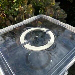 Puede incluir: Contenedor de almacenamiento de pl&aacute;stico transparente con tapa blanca y cierre circular. El contenedor est&aacute; vac&iacute;o.