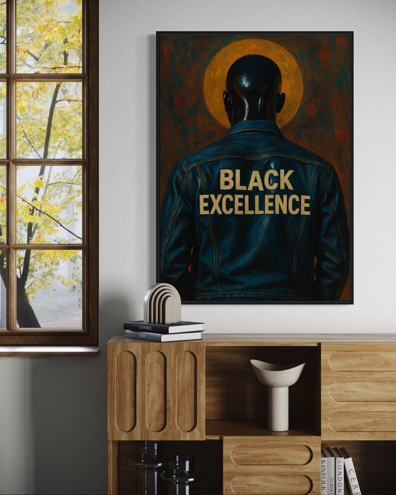 Puede incluir: Obra de arte enmarcada que presenta a una persona con una chaqueta vaquera azul con las palabras "BLACK EXCELLENCE" en letras doradas. La obra tiene un fondo oscuro con un halo dorado. La imagen se muestra en una habitaci&oacute;n con muebles de madera.