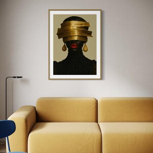 May include: Framed art print featuring a portrait of a person with a gold head wrap and gold teardrop earrings. The person has red lipstick and is wearing a black turtleneck. The artwork is displayed on a neutral wall above a yellow sofa.