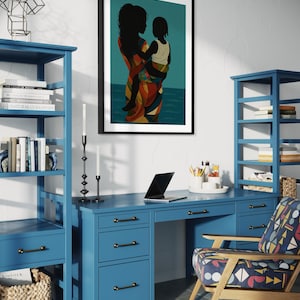 May include: A framed art print depicting a mother and child in silhouette, set against a teal background. The mother wears a colorful patterned dress. The print hangs above a blue desk and bookshelves, creating a home office setting.