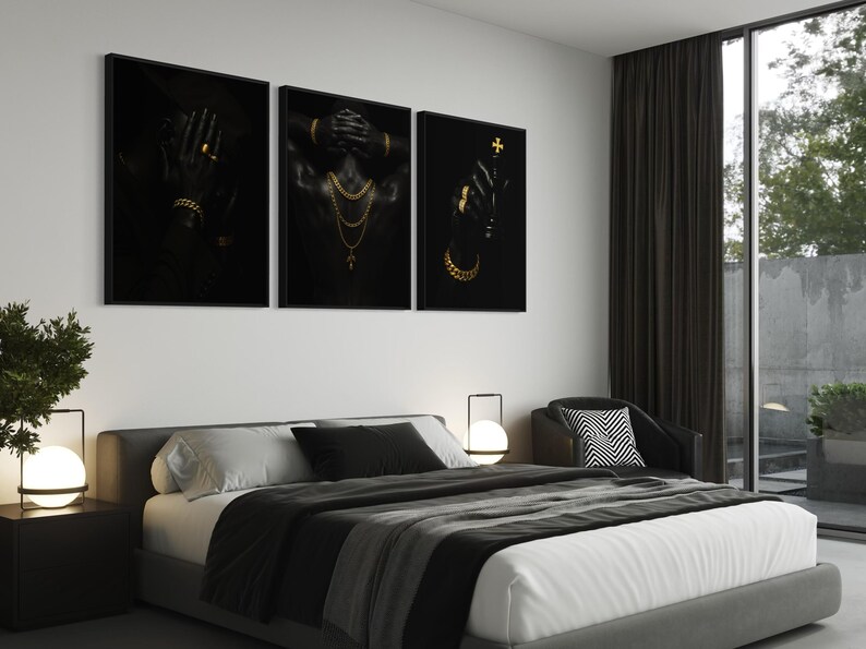May include: Three framed black and gold art prints. The prints feature figures adorned with gold jewelry. The first print shows a hand with a ring and bracelet. The second print shows a figure with gold necklaces. The third print shows a hand holding a cross.