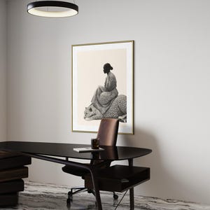 May include: An interior design scene featuring a framed artwork with a black and white illustration of a person seated on a leopard. A modern black desk, brown leather chair, and a circular light fixture are also visible.