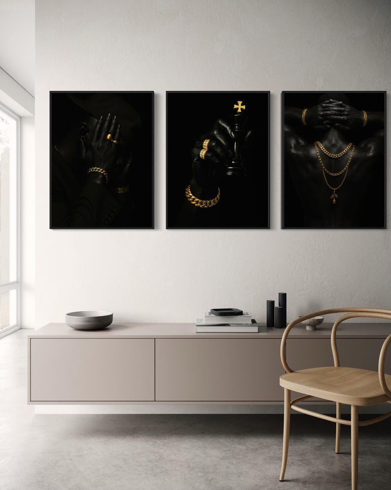 May include: Set of three framed art prints featuring black and gold imagery. One print shows a person wearing a hat and gold jewelry, another holds a chess piece, and the third displays a person with gold necklaces and bracelets.