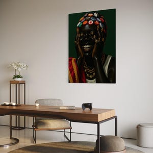 May include: A framed art print featuring a person with a dark complexion, adorned with a headpiece made of bottle caps. The person is laughing, wearing gold jewelry and a white top, set against a dark green background.
