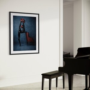 May include: A framed art print showing a black sculpture of a dancer holding a bouquet of red roses. The dancer is leaning against a red armchair. The background is a dark blue.