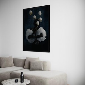May include: A framed art print featuring a person with white flowers and a white ruffled garment against a dark blue background. The artwork is displayed above a light gray sectional sofa and a marble-topped coffee table.