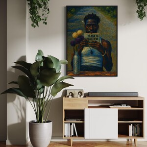 Puede incluir: Una obra de arte enmarcada representa a una persona sosteniendo un libro con el texto "BLACK IS BEAUTIFUL". La obra de arte cuelga sobre un mueble de madera con una puerta blanca. Tambi&eacute;n se ven una gran planta en maceta y plantas colgantes.