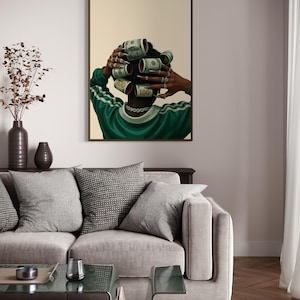 May include: A framed art print depicts a person with dollar bills rolled into curlers. The person wears a green and white striped shirt and a silver chain. The artwork is displayed above a gray sofa with decorative pillows.