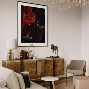 May include: An interior design scene featuring a framed artwork of a person holding a cocktail glass. The artwork is above a wooden cabinet with decorative items. A sofa, chair, and side table complete the room's decor. A chandelier hangs from the ceiling.