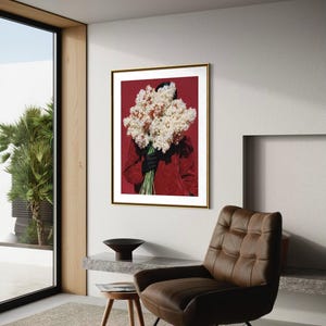May include: A framed art print featuring a person holding a large bouquet of white and cream-colored flowers against a deep red background. The person is wearing a red jacket and black gloves. The artwork is in a gold frame.