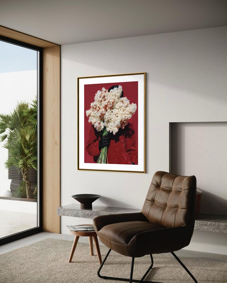 May include: A framed art print featuring a person holding a large bouquet of white and cream-colored flowers against a deep red background. The person is wearing a red jacket and black gloves. The artwork is in a gold frame.