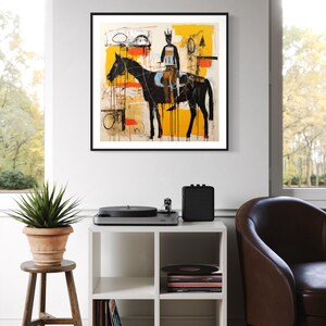 May include: Abstract art print of a black horse and rider against a yellow and cream backdrop, framed in black. A white cube shelf displays a record player, speaker, and vinyl records. The artwork hangs on a white wall.