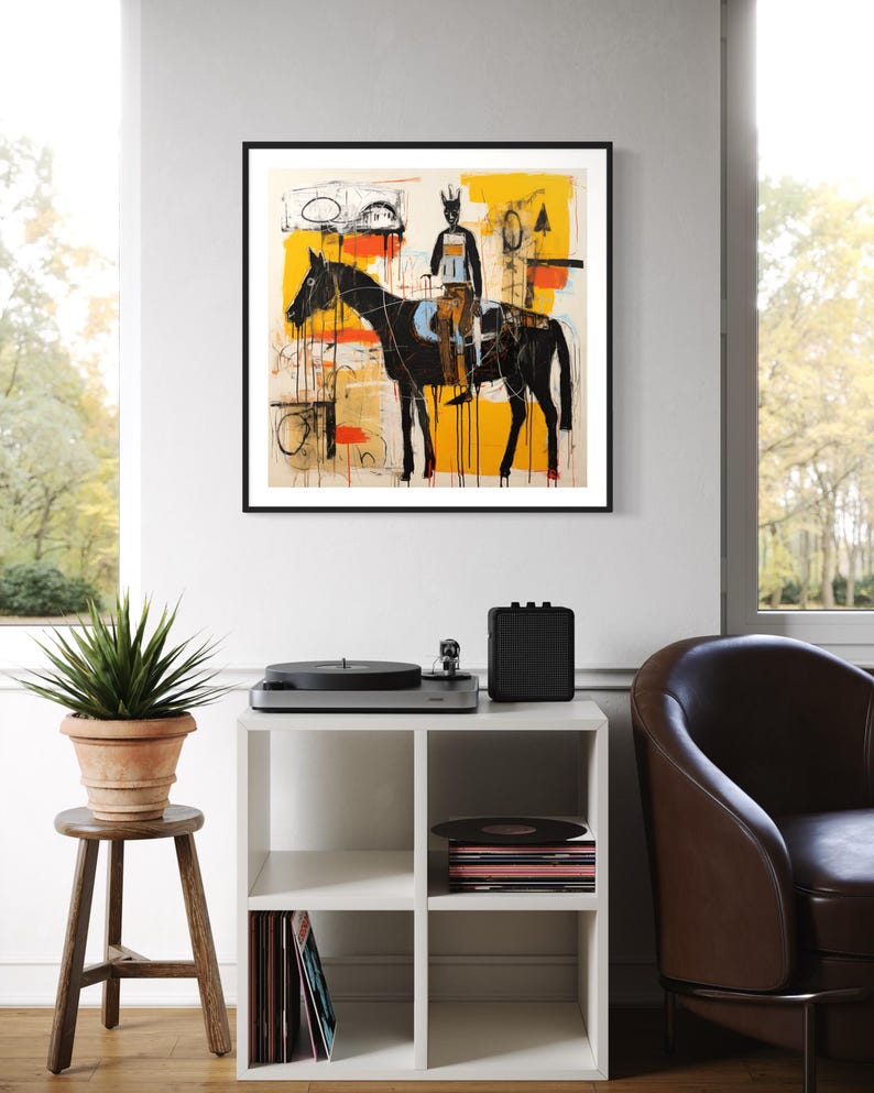 May include: Abstract art print of a black horse and rider against a yellow and cream backdrop, framed in black. A white cube shelf displays a record player, speaker, and vinyl records. The artwork hangs on a white wall.