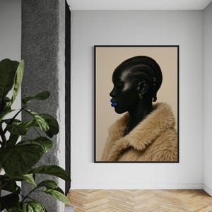 May include: A framed portrait of a person with dark skin, blue lipstick, and a tan faux fur coat. The person's hair is styled in braids. The portrait hangs on a white wall in a room with a wooden floor.