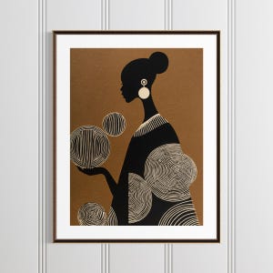May include: Framed art print featuring a black silhouette of a person with a bun, wearing large earrings, and a patterned dress. The person is holding several white and black striped and swirled spheres against a brown background.
