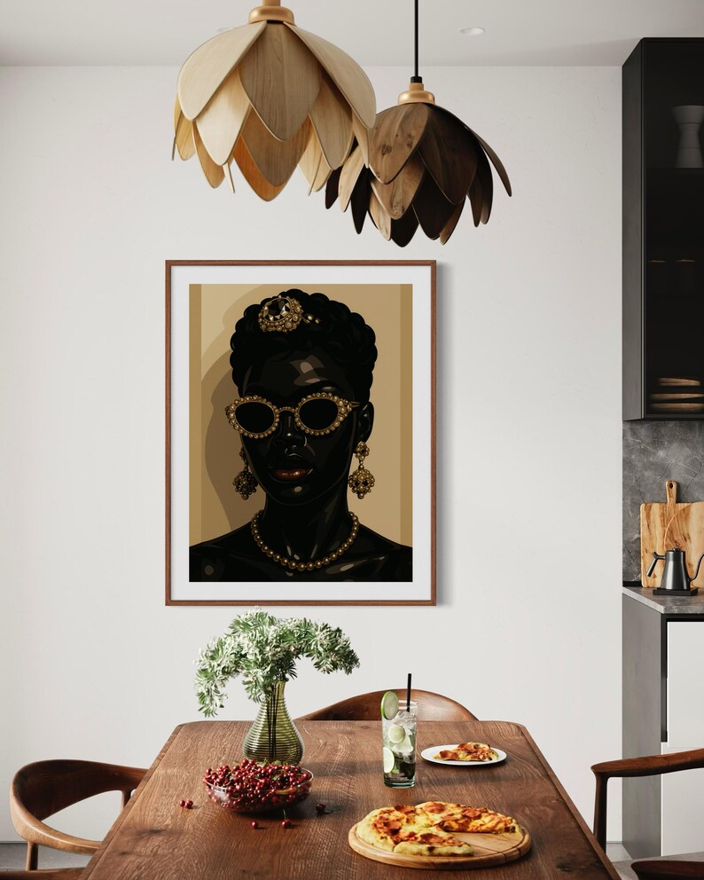 May include: A framed art print featuring a stylized portrait of a woman with dark skin, wearing gold-rimmed sunglasses, a pearl necklace, and ornate earrings. The artwork is set against a neutral background, with a brown wooden frame. The image is displayed in a dining room setting.