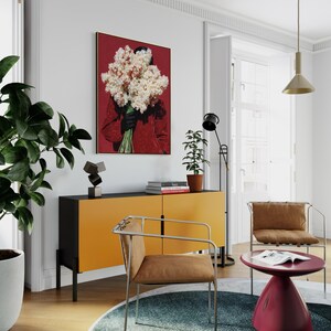 May include: An interior design scene featuring a modern living room. A large framed artwork with a red background and a person holding flowers hangs on the wall. A yellow and black cabinet, two chairs, a red side table, and a round rug complete the space.