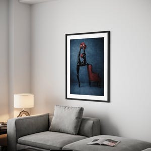 May include: A framed art print showing a black sculpture of a dancer with a bouquet of red flowers. The dancer is positioned in front of a red armchair against a dark blue background. The artwork is displayed in a modern living room.