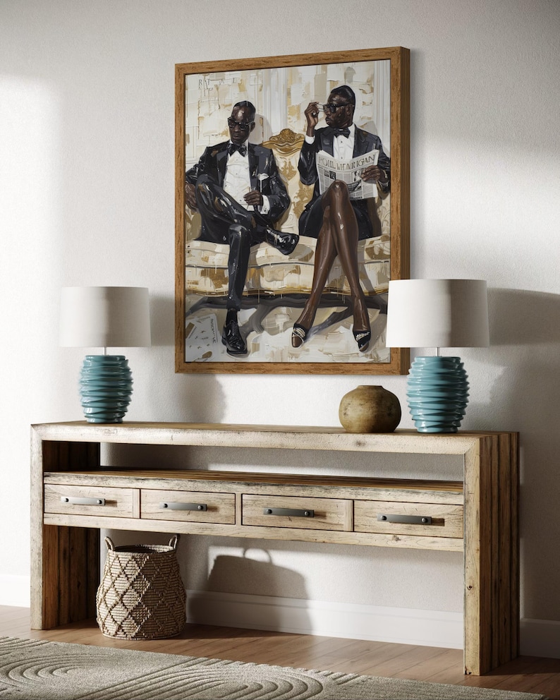 May include: A framed artwork depicts two figures in formal attire, seated on a sofa. Below, a light wood console table features drawers, a woven basket, and two turquoise lamps with white shades. A neutral rug completes the scene.