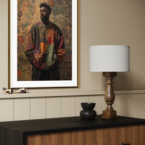 K&ouml;nnte beinhalten: Gerahmter Kunstdruck mit einem Portr&auml;t einer Person in einem farbenfrohen Patchwork-Pullover. Das Kunstwerk ist vor einem floralen Hintergrund mit einem goldenen Rahmen. Eine Holzlampe und eine schwarze Schale stehen auf einem dunklen Holzschrank.