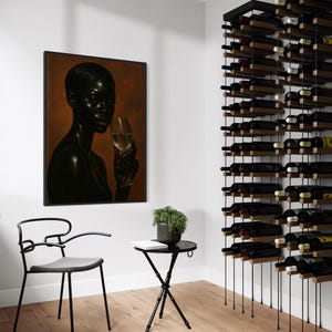 May include: A modern wine room featuring a black metal wine rack filled with bottles. A framed portrait hangs on the wall, and a small black table with a plant and chair are in the foreground. The room has a minimalist design with light-colored walls and hardwood floors.