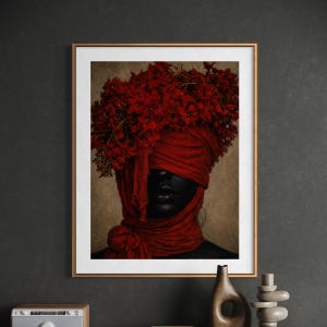 Puede incluir: Impresión artística enmarcada que representa a una persona con piel negra, ojos cubiertos por una tela roja y una corona de flores rojas. Los labios de la persona están pintados de negro. La obra de arte está en un marco dorado.