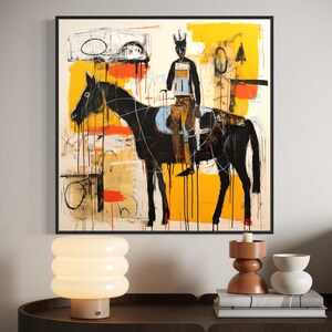 May include: Abstract artwork depicting a black horse and rider with a yellow, orange, and white background. The painting is framed in black and hangs on a white wall. The style is modern and expressive, with a focus on bold colours and brushstrokes.