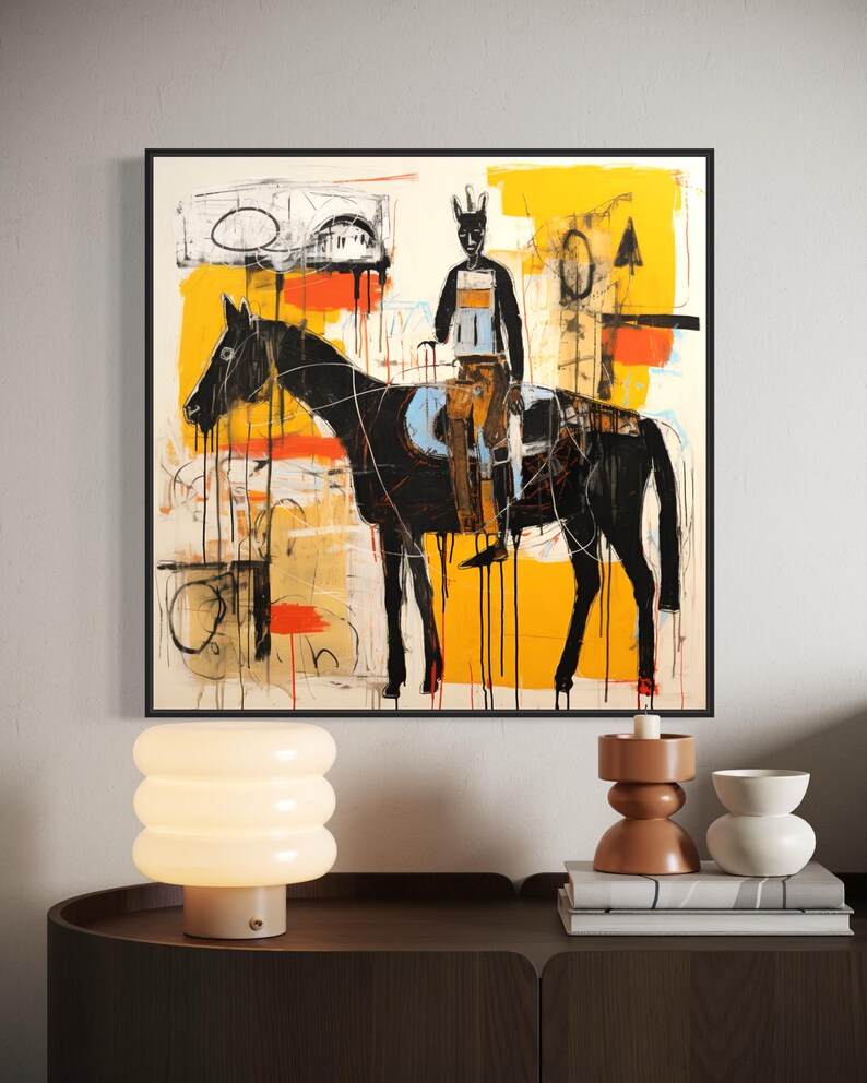 May include: Abstract artwork depicting a black horse and rider with a yellow, orange, and white background. The painting is framed in black and hangs on a white wall. The style is modern and expressive, with a focus on bold colours and brushstrokes.