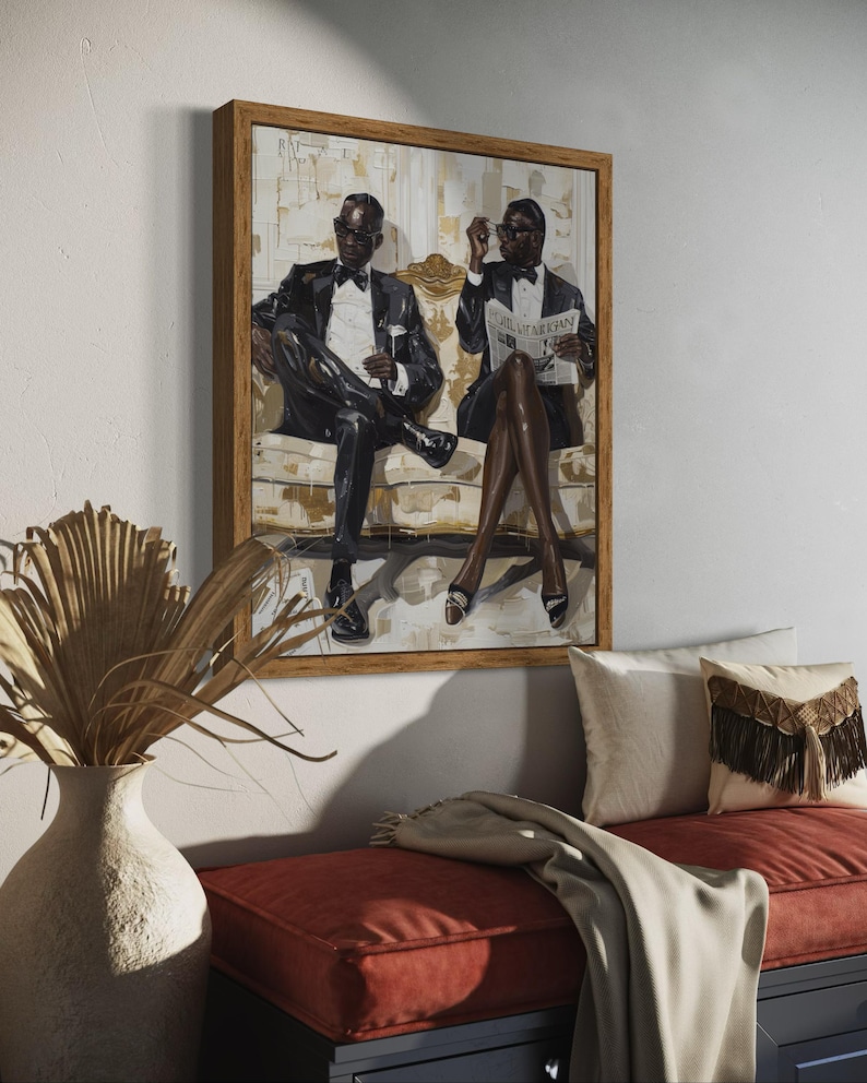 May include: A framed artwork depicts two figures in formal attire seated on a sofa. The figures are wearing black suits, bow ties, and sunglasses. One holds a glass, the other a newspaper. The artwork is displayed above a red bench with decorative pillows.