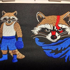 May include: Embroidered raccoon designs on a black background. One raccoon is in boxing attire, with blue shorts, gloves, and a white vest. The other has a red stripe and a blue scarf.