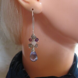 May include: Silver dangle earrings with a cluster of amethyst, rose quartz, and labradorite gemstones. The earrings have a teardrop-shaped amethyst gemstone hanging from the bottom.