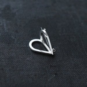 May include: A silver heart-shaped brooch with a small, round accent at the bottom.